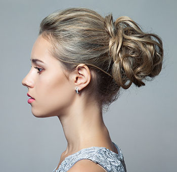 Portret lateral al unei femei care își arată noul stil de păr după ce a rezervat un serviciu de salon de coafură folosind aplicația Planfy.com.