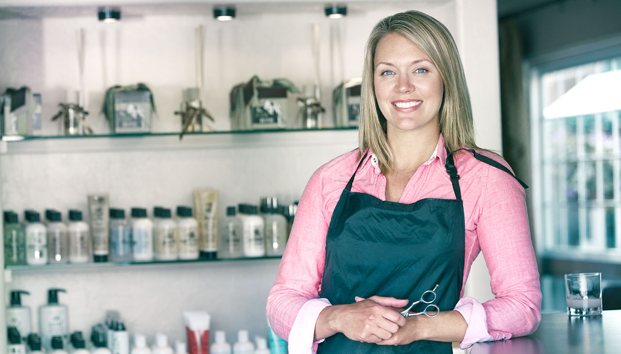 Kvinde frisørsalon ejer smilende ved brug af Planfy bookingsystem.