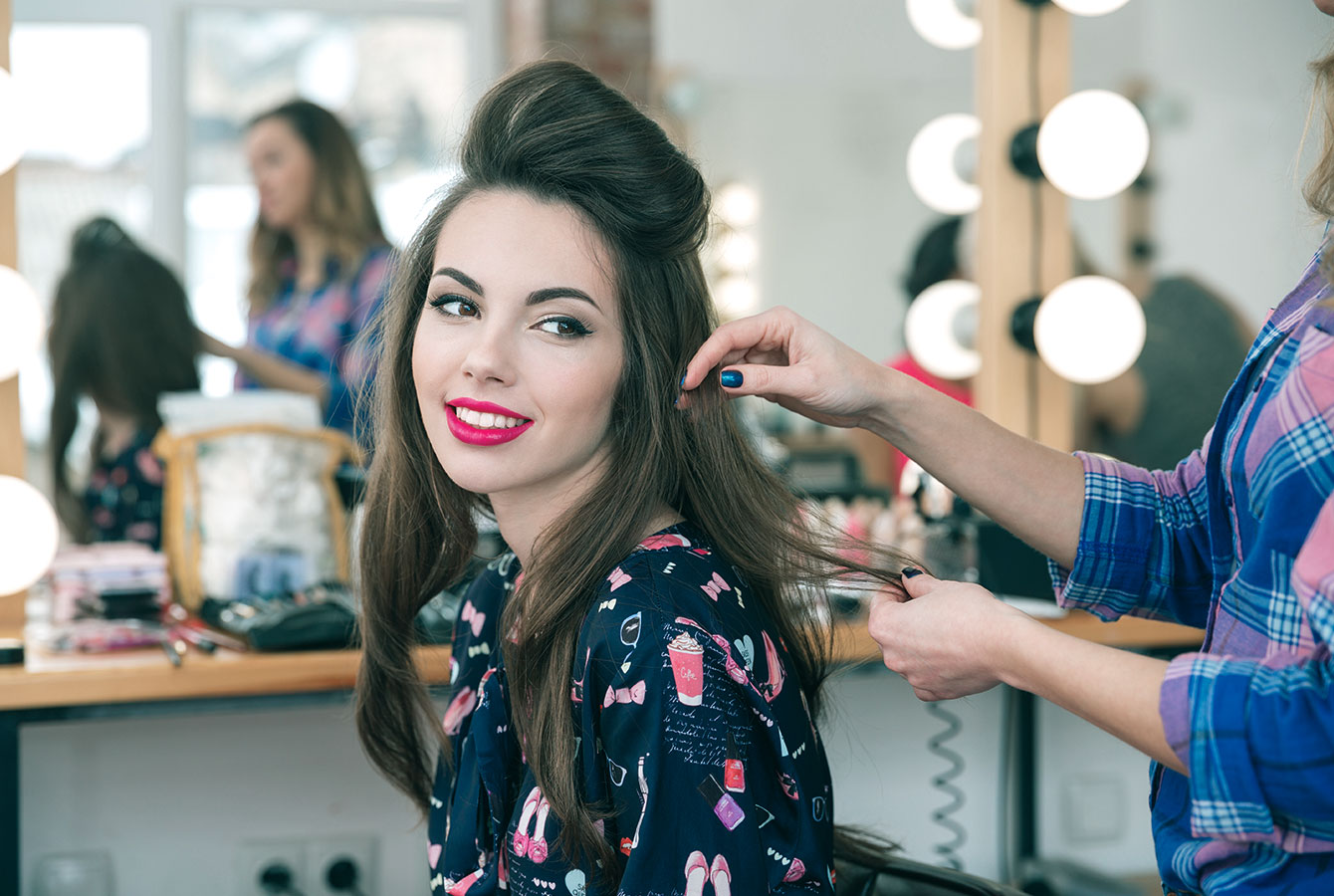 Penata rambut profesional menata rambut pelanggan di salon rambut. Layanan dipesan menggunakan aplikasi Planfy.