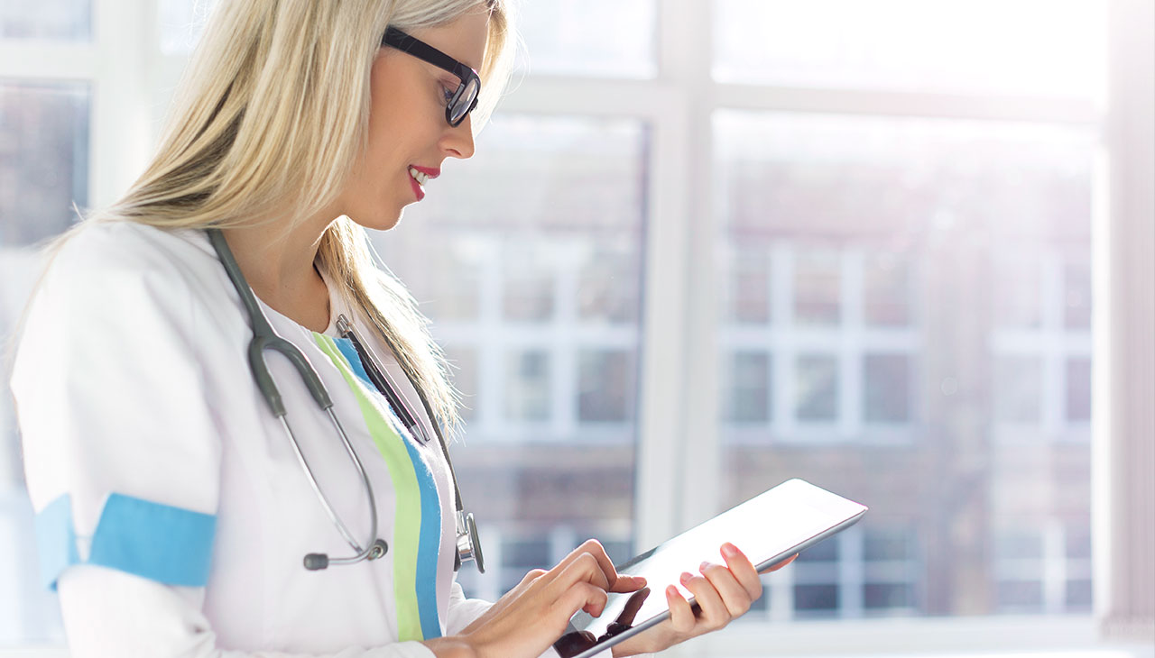 Medico donna che gestisce le prenotazioni online utilizzando il sistema di prenotazione Planfy sul suo dispositivo tablet.