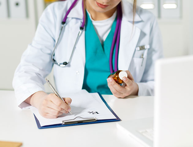 Uma médica em sua mesa está preenchendo um formulário.