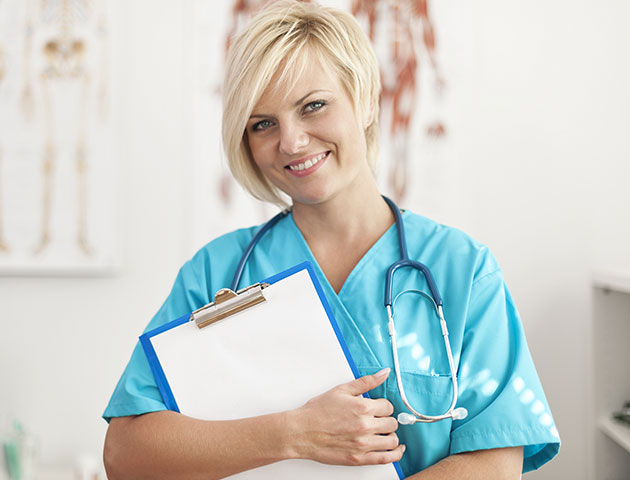 O profesionistă medicală de sex feminin care zâmbește în timp ce așteaptă următorul pacient care și-a rezervat programul folosind aplicația de rezervare Planfy.