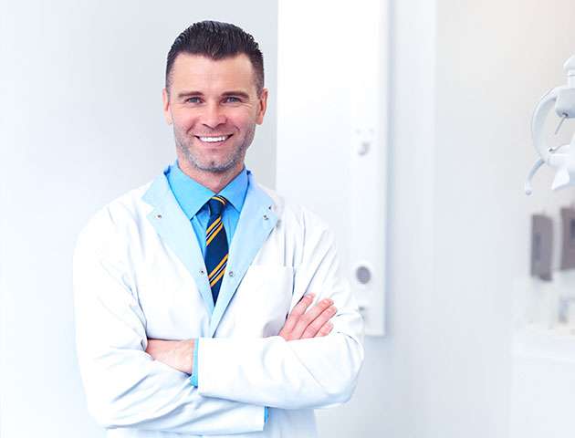 Odontologas vyras stovi odontologijos klinikoje ir laukia kito paciento. 