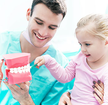 Dentista che mostra a un paziente come lavarsi i denti correttamente.