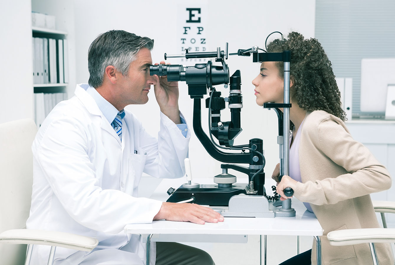Profesional perawatan mata sedang menguji mata pasien wanita di klinik dokter mata.